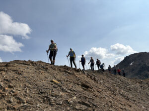 Group of 10 women with hiking equipment walking in a line during a guided hiking retreat on the Esplanade Range in BC.