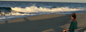Woman sitting meditating with the Pacific ocean