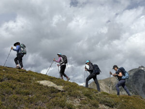 four women in hiking gear with walking poles walking along esplanade range