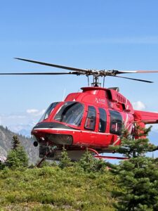 Closeup of a helicopter with blue skies and the Rocky mountains in the background