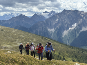 A group of five women hiking with mountains in the background
