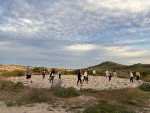 A group of people walking a labrinth, storm clouds overhead