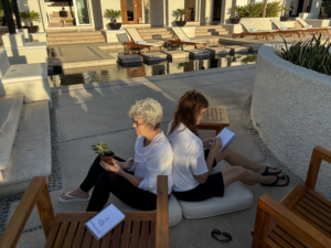 Two women back to back sketching plants.